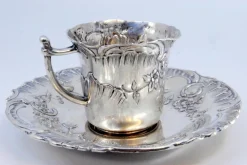 Tasse und Untertasse aus geprägtem Silber mit floralen Motiven